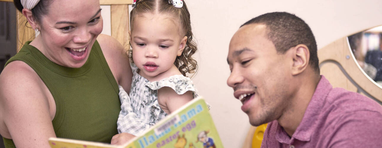 A mother, father, and toddler read a book together at the Leon County Public Library.