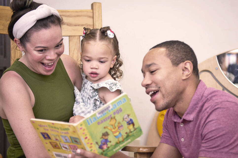 A mother, father, and toddler read a book together at the Leon County Public Library.